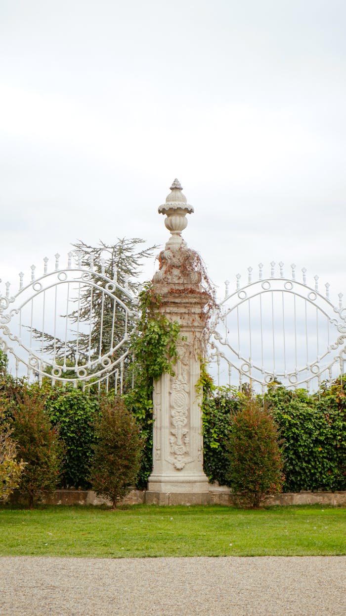 Elegant stone column surrounded by lush greenery, set against an overcast sky.
