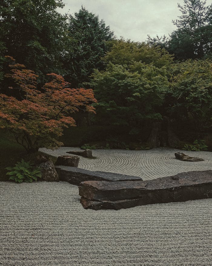 Peaceful Japanese garden scene featuring raked gravel and lush greenery.