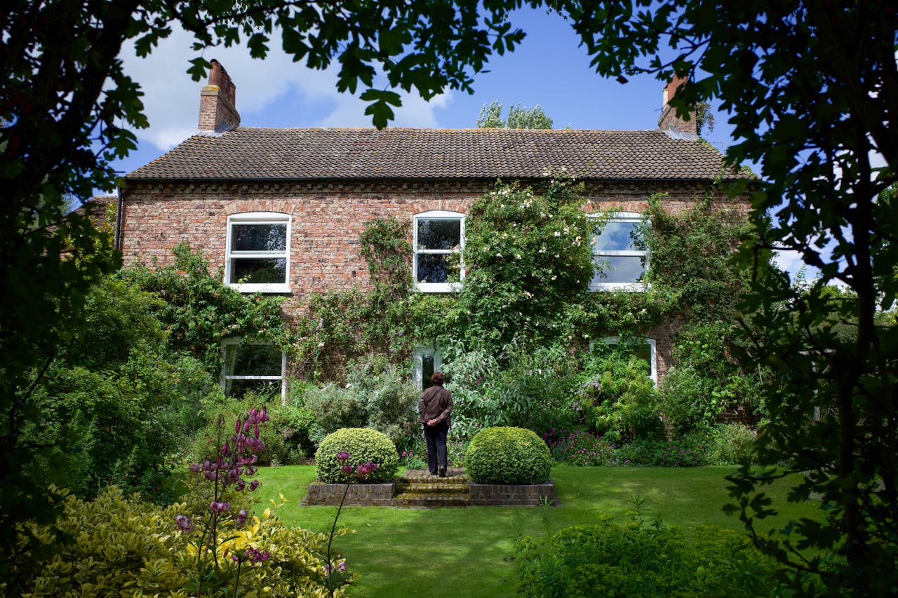 about-01 Discover the tranquil beauty of an English garden with lush greenery and a classic brick house in York, England.